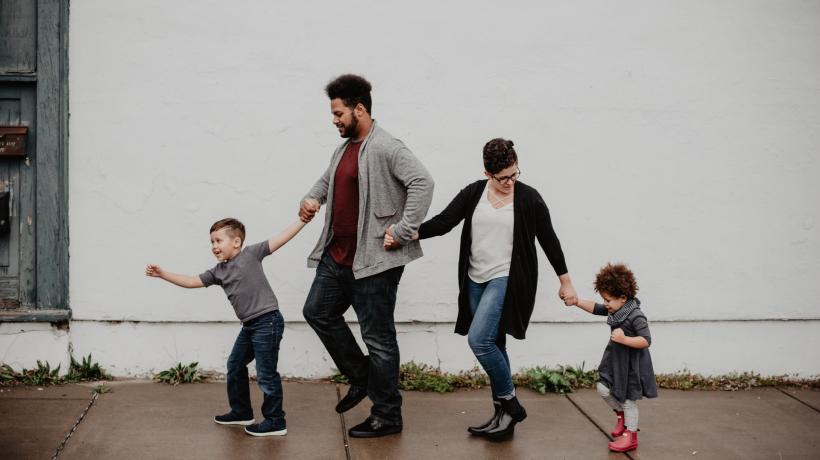 Auf dem Bild ist eine vierköpfige Familie zu sehen: Ein schwarzer Mann, eine weiße Frau und zwei Kinder.