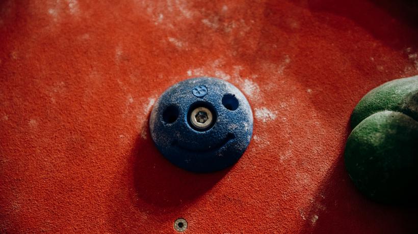 Ein blauer Boulderstein an einer roten Wand.
