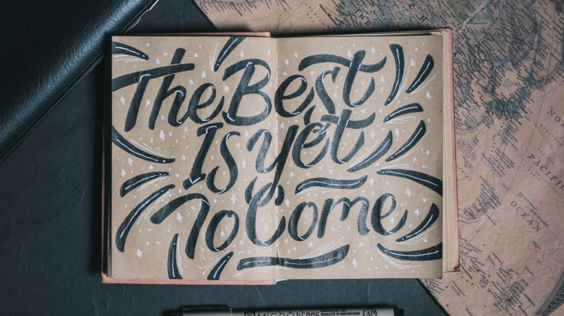 Auf den Seiten eines aufgeschlagenen Notizbuchs steht "The Best is yet to Come".