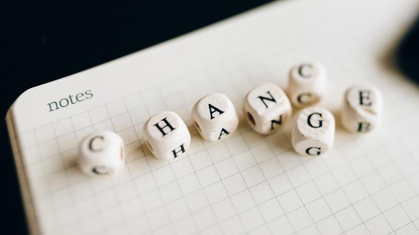 Auf einem leeren Notizblock liegen Würfel, die mit Buchstaben bedruckt sind. Sie ergeben das Wort Change bzw. Chance - je nachdem wie der vorletzte Würfel gelegt wird.