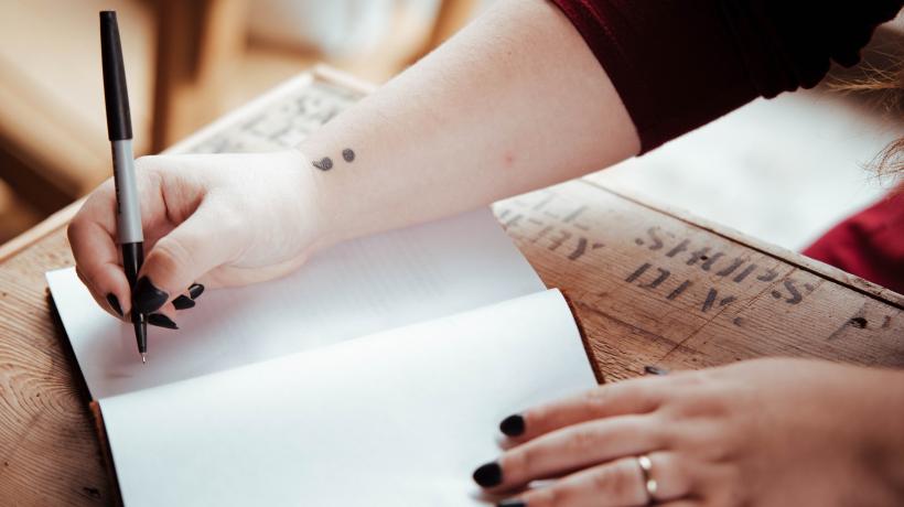 Ein offenes Notizbuch, in das eine Frau schreibt